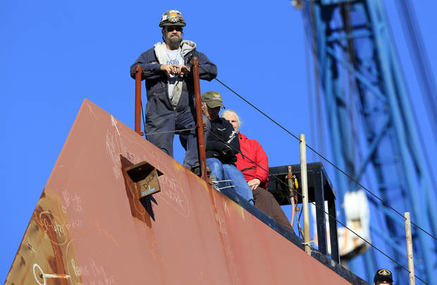 Workers watch a christening ceremony at Bath Iron Works from the bow of the future USS Michael Monsoor in Bath. With labor relations already rocky, Bath Iron Works and the union representing shipbuilders have decided to get off to an early start on informal contract negotiations. The company wants to get a headstart on negotiations aimed at helping the shipyard win contracts for new Coast Guard cutters.